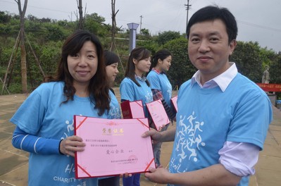 重慶江北希爾頓逸林酒店人力資源總監曹麗女士（左一）從重慶市精神衛生院院長朱學文先生（右一）手中接過“第六屆重慶慧靈慈善慢跑愛心企業”榮譽證書